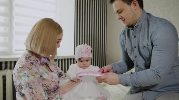 Lycklig familj leker med sin lilla dotter på en vit säng. — Stockvideo