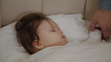 İki ebeveyn çocuklarının yatağında dikilip onu kollarına götürür..