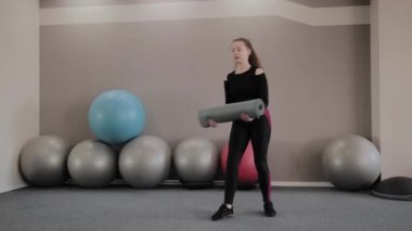 Kız spor salonunda fitness mat kapsar.