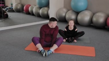 Yağ kadın ve erkek fitness paspaslar üzerinde germe.