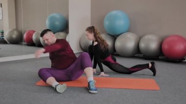 Yağ kadın ve erkek fitness paspaslar üzerinde germe.