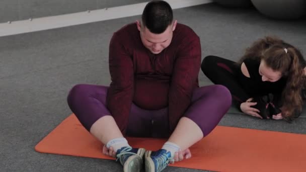 在健身垫上伸展运动的胖女人和男人. — 图库视频影像