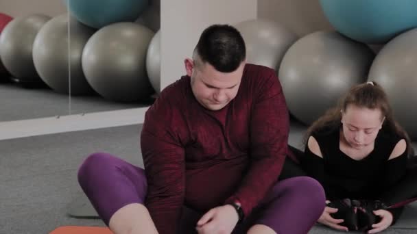 Товста жінка і чоловік тягнеться на фітнес килимки . — стокове відео