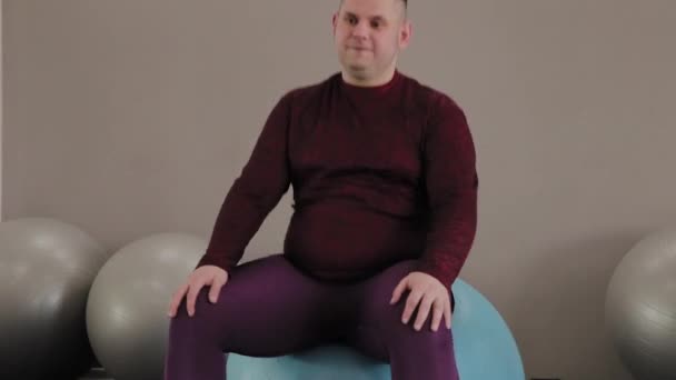 Hombre gordo alegre entrena en la pelota de fitness . — Vídeos de Stock