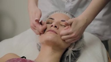 Kadın Spa salonunda yüz masajı yapıyor.
