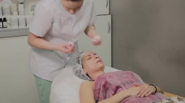 Bir kadın güzellik salonunda özel mendiller ile temizlenir.
