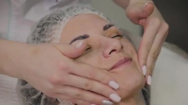 Kadın Spa salonunda yüz masajı yapıyor.