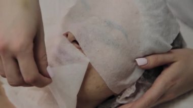 Bir kadın güzellik salonunda özel mendiller ile temizlenir.