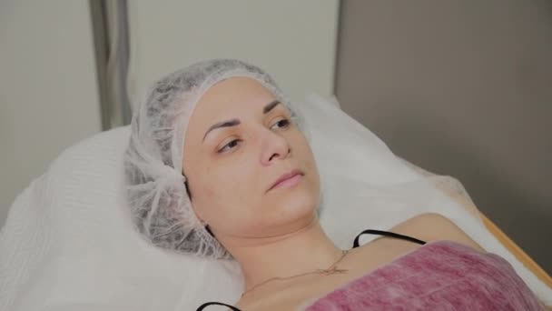 Hermosa mujer joven en albornoz acostada y esperando procedimiento de cuidado facial en el salón de spa de lujo — Vídeo de stock