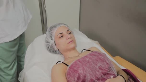 Krásná mladá žena v županu leží a čeká postup péče o pleť v luxusní spa salonu — Stock video