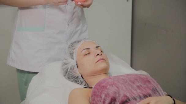 Kosmetikerin setzt Maske auf Gesicht liegender Frau in Wellness-Salon drinnen. — Stockvideo