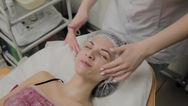 Mujer haciendo masaje facial en el salón de spa . — Vídeos de Stock