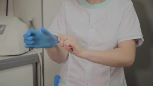 Selbstbewusste Ärztin mit Maske und Mütze im Krankenhauszimmer, die blaue medizinische Handschuhe anzieht. Ärztin bei der Arbeit. Gesundheitskonzept. Laborangestellte. — Stockvideo