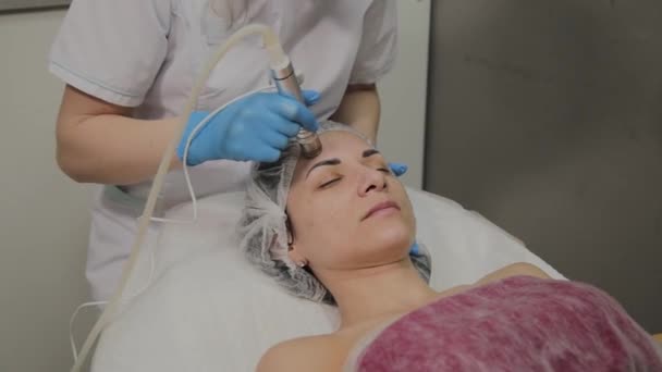 Een professionele schoonheidsspecialist maakt een vrouw vacuüm reinigen van het gezicht in een schoonheidssalon. Cosmetische innovaties. — Stockvideo