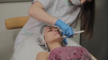 Profesyonel bir Kozmetolog bir kadın güzellik salonunda yüz temizleme vakum yapar. Kozkolojik yenilikler.