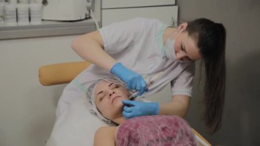 Profesyonel bir Kozmetolog bir kadın güzellik salonunda yüz temizleme vakum yapar. Kozkolojik yenilikler.