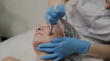 Profesyonel bir Kozmetolog bir kadın güzellik salonunda yüz temizleme vakum yapar. Kozkolojik yenilikler.