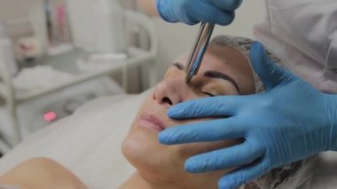 Profesyonel bir Kozmetolog bir kadın güzellik salonunda yüz temizleme vakum yapar. Kozkolojik yenilikler.