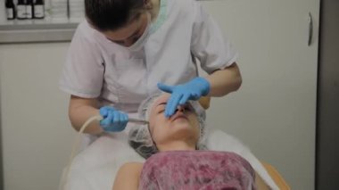 Profesyonel bir Kozmetolog bir kadın güzellik salonunda yüz temizleme vakum yapar. Kozkolojik yenilikler.