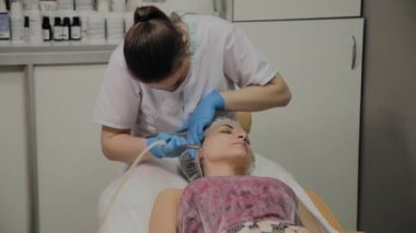 Profesyonel bir Kozmetolog bir kadın güzellik salonunda yüz temizleme vakum yapar. Kozkolojik yenilikler.