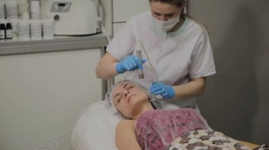 Profesyonel bir Kozmetolog bir kadın güzellik salonunda yüz temizleme vakum yapar. Kozkolojik yenilikler.
