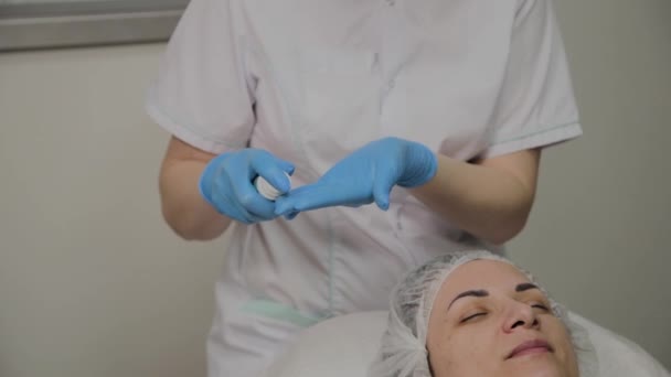 Профессиональный косметолог берет в руки массажный крем . — стоковое видео
