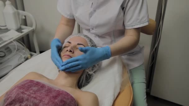 Mujer haciendo masaje facial en el salón de spa . — Vídeos de Stock