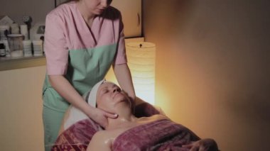 Profesyonel Kozmetolog yaşlı bir kadına masaj yapar. Kozkolojik yenilikler