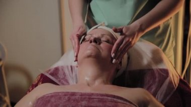 Profesyonel Kozmetolog yaşlı bir kadına masaj yapar. Kozkolojik yenilikler