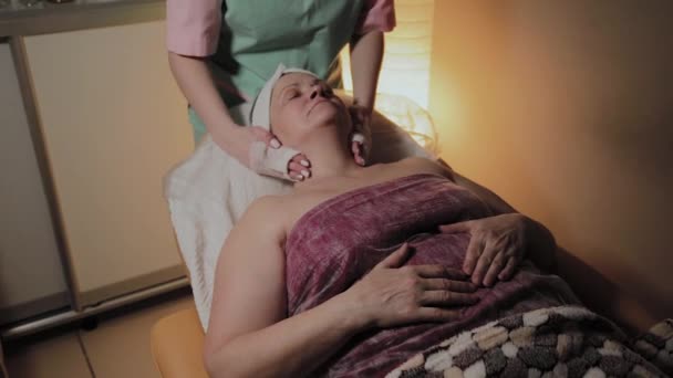 Een professionele schoonheidsspecialiste bereidt het gezicht van een oudere vrouw voor de procedure. Cosmetische innovaties — Stockvideo