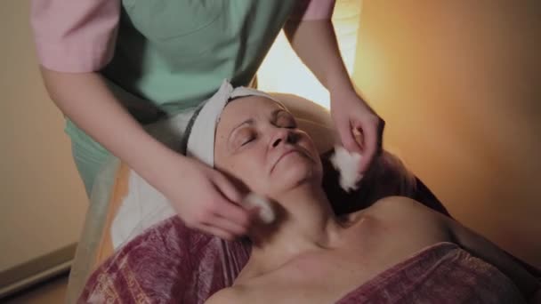 Un esthéticien professionnel prépare le visage d'une femme âgée pour l'intervention. Innovations cosmétologiques — Video