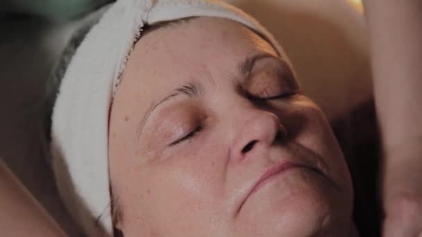 Профессиональный косметолог готовит лицо пожилой женщины к процедуре. Косметологические инновации — стоковое видео