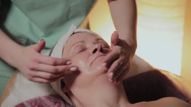 Professionelle Kosmetikerin massiert eine ältere Frau. Kosmetologische Innovationen — Stockvideo