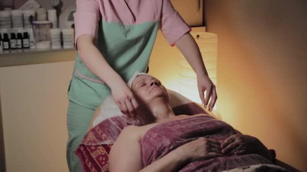 Cosmetologo professionista fa massaggio a una donna anziana. Innovazioni cosmetologiche — Video Stock