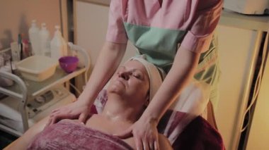 Profesyonel Kozmetolog yaşlı bir kadına masaj yapar. Kozkolojik yenilikler