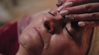 Profesyonel Kozmetolog yaşlı bir kadına masaj yapar. Kozkolojik yenilikler