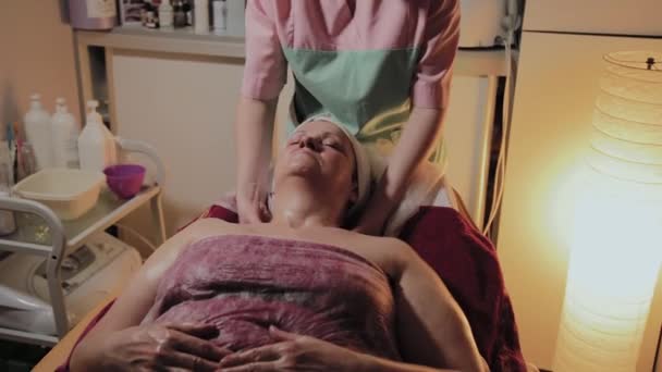 Professionele schoonheidsspecialist maakt massage aan een oudere vrouw. Cosmetische innovaties — Stockvideo