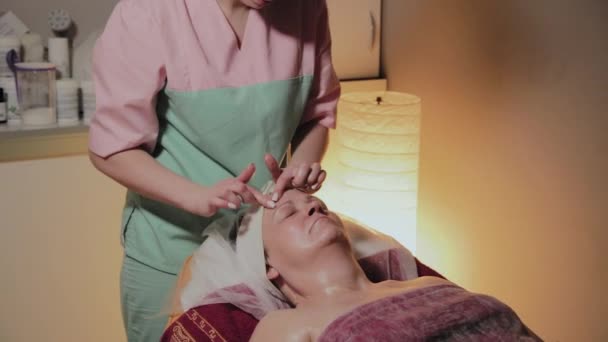 Professional cosmetologist makes massage to an elderly woman. Cosmetological innovations — Stock Video