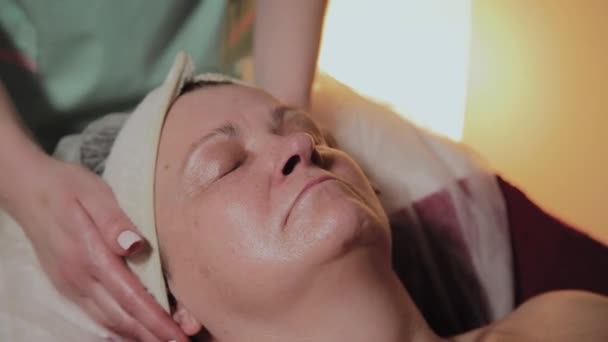 Професійний косметолог робить масаж літній жінці. Косметологічні інновації — стокове відео
