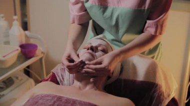 Profesyonel Kozmetolog yaşlı bir kadına masaj yapar. Kozkolojik yenilikler