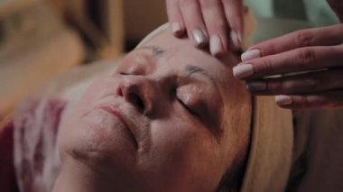 Profesyonel Kozmetolog yaşlı bir kadına masaj yapar. Kozkolojik yenilikler