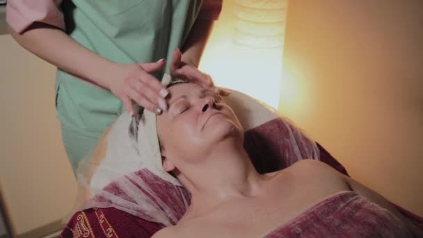 Profesjonalny kosmetolog sprawia, że masaż do starszej kobiety. Innowacje kosmetyczno-kosmetyczne — Wideo stockowe