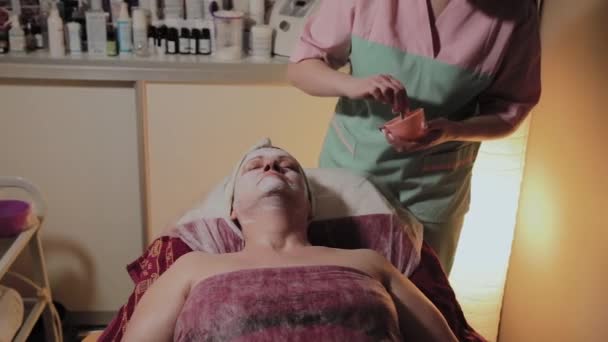 Un cosmetologo professionista applica una maschera per il viso a una donna anziana. Innovazioni cosmetologiche . — Video Stock