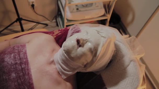 Mujer de edad bien arreglada está usando una máscara en el procedimiento en un salón de belleza . — Vídeo de stock