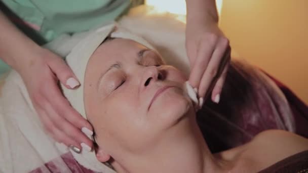 Ένας επαγγελματίας αισθητικός προετοιμάζει το πρόσωπο μιας γηραίας γυναίκας για τη διαδικασία. Καλλυννολογικές καινοτομίες — Αρχείο Βίντεο