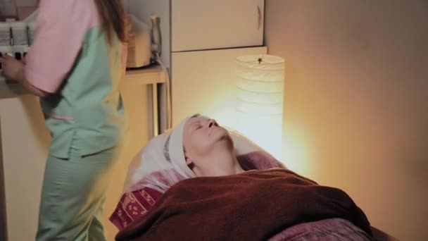 Un esthéticien professionnel prépare le visage d'une femme âgée pour l'intervention. Innovations cosmétologiques — Video