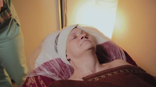 Een professionele schoonheidsspecialiste bereidt het gezicht van een oudere vrouw voor de procedure. Cosmetische innovaties — Stockvideo