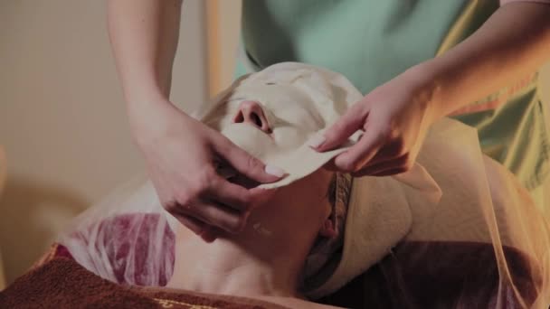 Profesjonalny kosmetolog usuwa maskę z twarzy starszej kobiety. Innowacje kosmetyczno-kosmetyczne. — Wideo stockowe