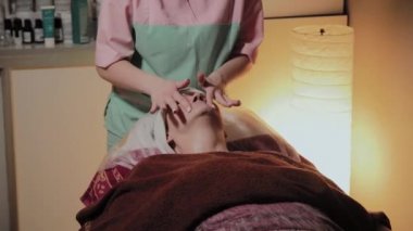 Profesyonel bir güzellik prosedürü için yaşlı bir kadının yüzünü hazırlar. Kozkolojik yenilikler