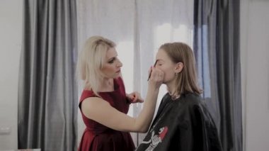 Makyaj sanatçısı güzel bir genç kıza profesyonel makyaj uygular. Makyaj yeni konsept.